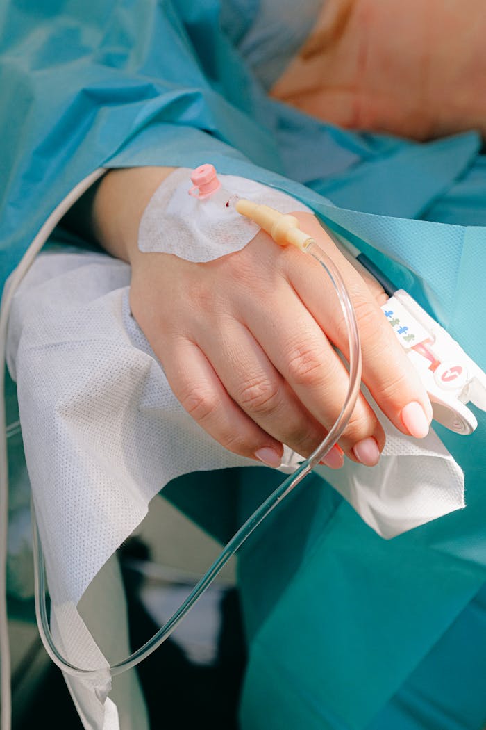 Close-up of a patient's hand receiving intravenous therapy in a hospital setting.